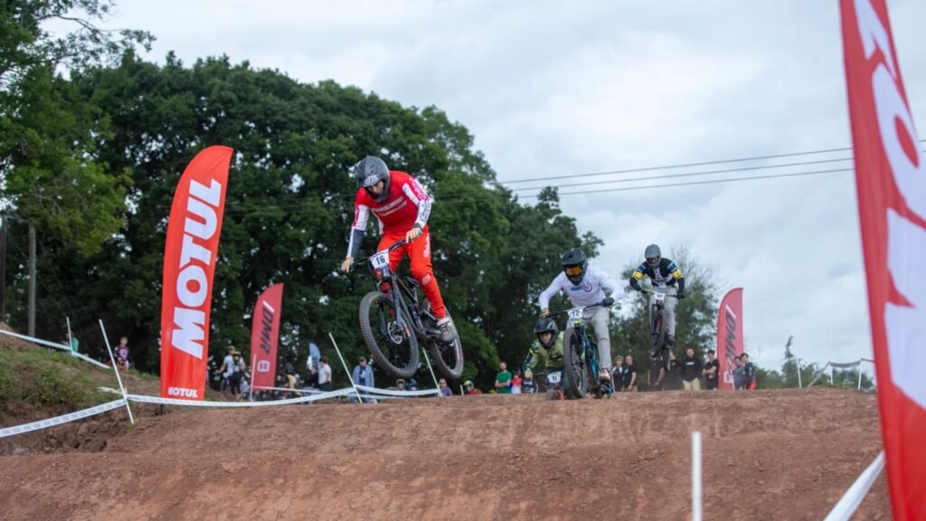 A man in red clothing racing a mountain bike track